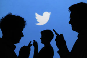 People holding mobile phones are silhouetted against a backdrop projected with the Twitter logo in this illustration picture taken in  Warsaw September 27, 2013. Twitter Inc, the eight-year-old online messaging service, gave potential investors their first glance at its financials on Thursday when it publicly filed its IPO documents, setting the stage for one of the most-anticipated debuts in over a year. Picture taken September 27.  REUTERS/Kacper Pempel (POLAND - Tags: BUSINESS TELECOMS LOGO) - RTR3FL8C